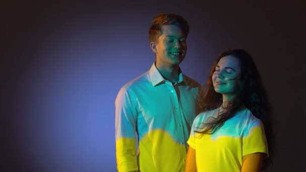 快乐的两个青少年在演播室里摆姿势，投射蓝色和黄色的乌克兰国旗 — 图库视频影像