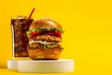 Sarı arka planda kola ile nefis bir hamburger.