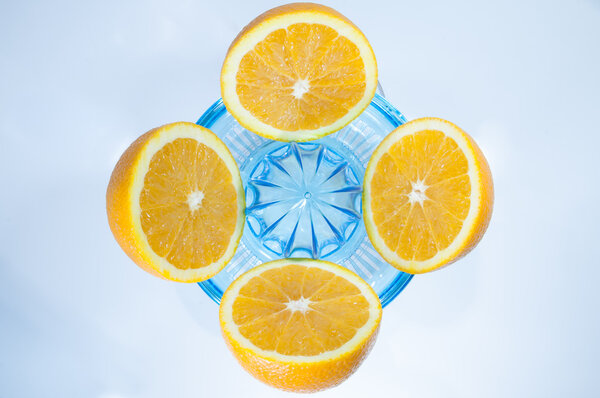 Four sliced oranges with a squeezer