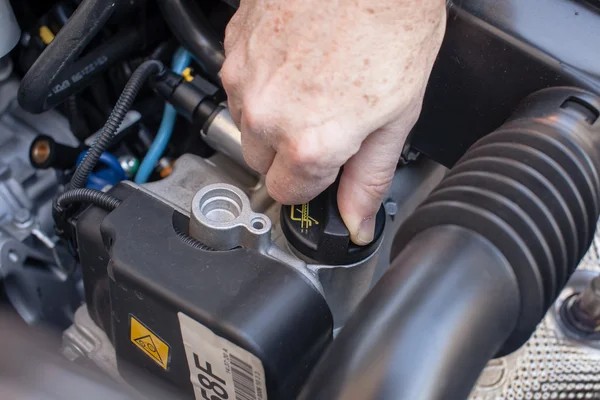 Main qui contrôle le bouchon d'huile dans un moteur de voiture de dernière génération — Photo