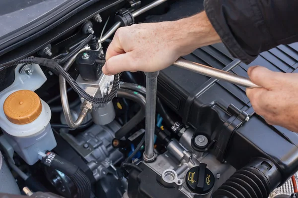 Mãos com uma chave que reparar um motor de carro — Fotografia de Stock