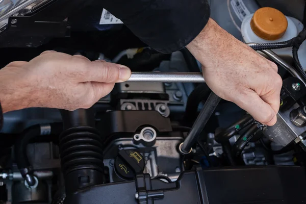 Manos con una llave inglesa que repara un motor de coche — Foto de Stock