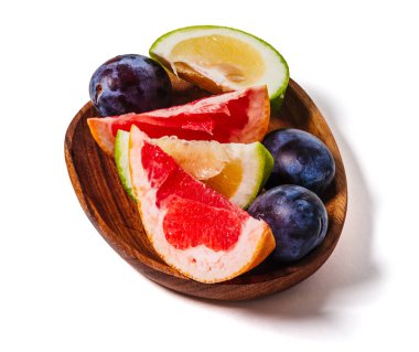 Beyaz arka planda izole edilmiş, ahşap bir tabakta greyfurt ve erik dilimleri. Taze yaz meyve kompozisyonu.