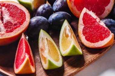 Tahta bir tahtanın üzerinde greyfurt ve erik dilimleri. Yaz meyveleri arka planı.