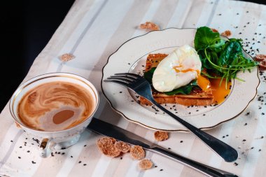Sağlıklı kahvaltı, haşlanmış yumurta ve yeşil salata yaprakları. Yumurta sarısı yayılmış.