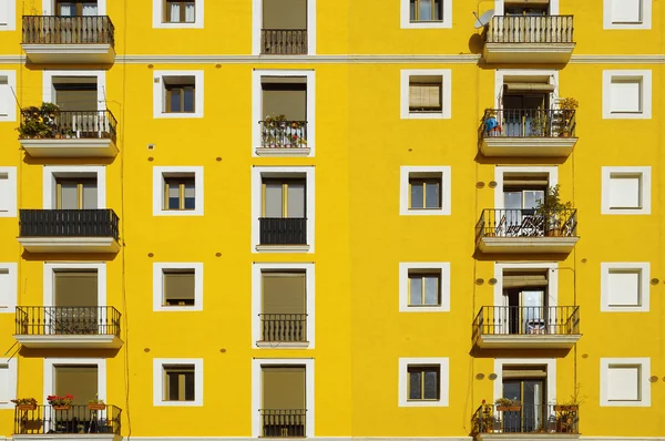 Fachada amarela. Algumas janelas de apartamento alinhadas fazendo linhas . — Fotografia de Stock