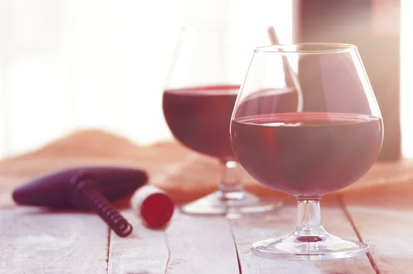 Två glas rött vin på en vit träbord, solnedgången ljus. — Stockfoto
