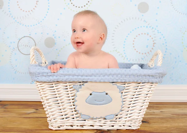 Adorable baby boy sitting in blue wicker basket — Stock Photo, Image