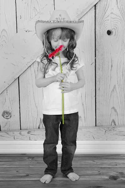 Adorável jovem cowgirl cheirando flor — Fotografia de Stock
