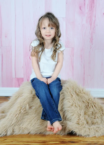 Adorable little girl posing on brown fur rug — Stock Photo, Image