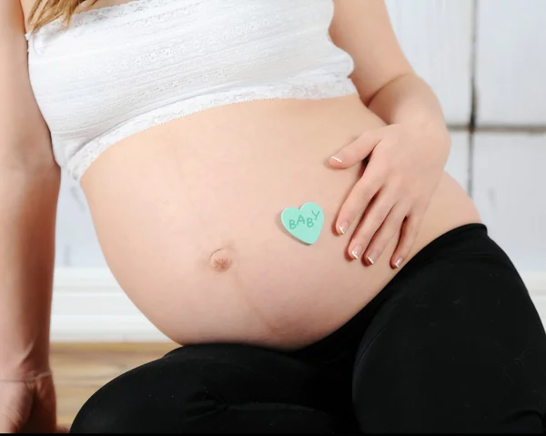 Primer plano de las mujeres embarazadas vientre con el bebé en el corazón —  Fotos de Stock