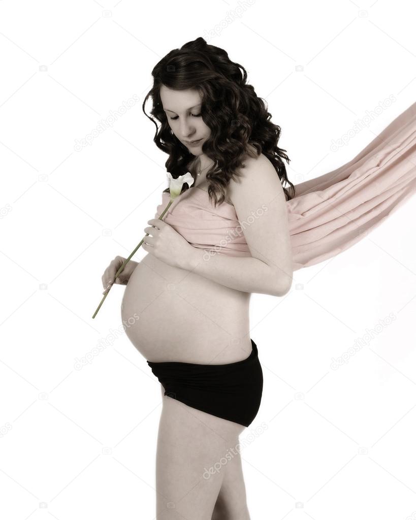 young pregnant woman in drape admiring a calla lily. isolated