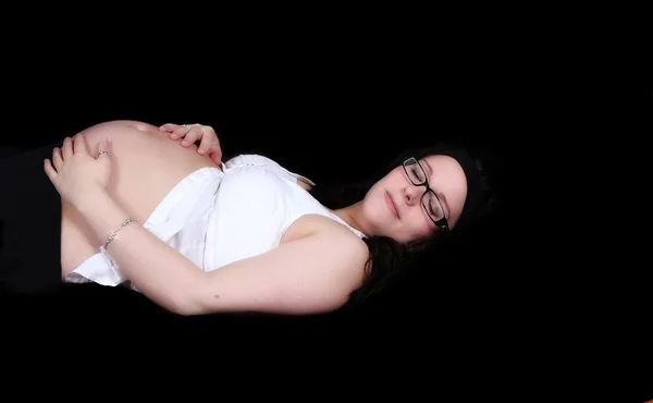 Красивая беременная женщина лежит, держа живот изолирован — стоковое фото