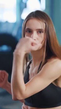 Enerjik ve dinamik bir jimnastik salonu. Kararlı genç bir kadının yoğun fitness eğitimini resmediyor.