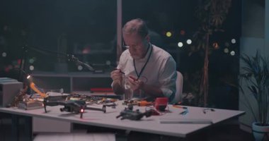 Kafkas mühendisi masa başında oturmuş mikroçip panosundaki demir maddeleri lehimliyor geceleri teknoji cihazını tamir ediyor..