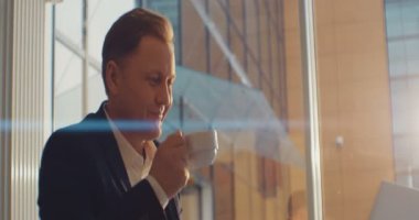 Dizüstü bilgisayar kullanan bir iş adamı bir kafede kahve içiyor. Mutlu hissettiriyor. RED Epic Camera 'da Çekim.