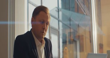 Kafede oturan ciddi bir adam dizüstü bilgisayar kullanıyor. İşadamı şaşırdı. Kahve iç. RED Epic Camera 'da Çekim.