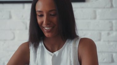 Bilgisayarın başında oturup görüntülü konuşma yapan genç, güzel mulatta kadını kapat. Evde, mutfakta. Mutlu hissettiriyor. Çubuklar. Modern tasarım. RED Epic Camera 'da Çekim.