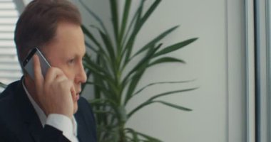 İş adamı ofiste telefonla konuşur. Endişeli hissediyorum. Üzücü ve tatminsiz. RED Epic Camera 'da Çekim.