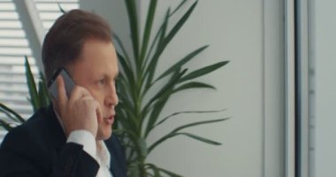 İş adamı ofiste telefonla konuşur. Endişeli hissediyorum. Üzücü ve tatminsiz. RED Epic Camera 'da Çekim.