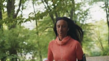 Parkta koşup kulaklıkla müzik dinleyen genç, güzel bir mulatta kadın. RED Epic Camera 'da Çekim.