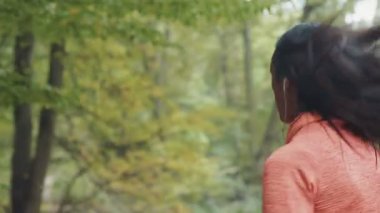 Parkta koşup kulaklıkla müzik dinleyen genç, güzel bir mulatta kadın. RED Epic Camera 'da Çekim.