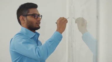 Mavi gömlekli bir işadamı, bir ofiste tahtaya yazı yazıyor. RED Epic Camera 'da Çekim.