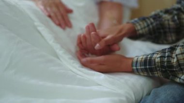 Aşk ve destek kavramı. Hastane odasında iletişimi destekleyen yaşlı annesinin elini tutan genç bir kadın. Kıdemli bayan hasta. Portreler.