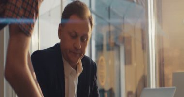 Kafede oturan ciddi bir adam dizüstü bilgisayar kullanıyor. Kahve iç. RED Epic Camera 'da Çekim.