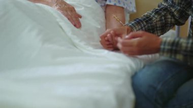 Hastanedeki ameliyattan önce aile yaşlı büyükanneyi destekliyor. Hastane odasında yatan yorgun, üzgün kadın hastanın portresi. Hastalık, sağlık, tedavi kavramı.