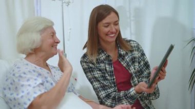 Hastane odasındaki anne ve kızının tablet bilgisayarda akrabalarıyla görüntülü sohbetleri kutlu olsun. Sağlık sigortası. Teknoloji. Uzak ilişkiler.