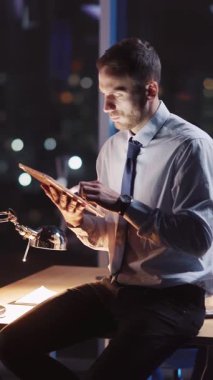 Genç bir profesyonel gece gösterişli, çağdaş ofis ortamında veri analiziyle meşgul olur.