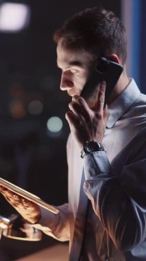 Odaklanmış bir işadamı, geceleri hareketli bir şehir ortamında notlar alırken bir telefon görüşmesi yapıyor..