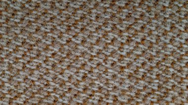 Arka plan olarak kullanılacak kumaş dokusunun makro fotoğrafı. Kumaş, turuncu ve gri ipliklerin karışımından yapılmış. Sentetik ve yün karışımı. Soyut desen.