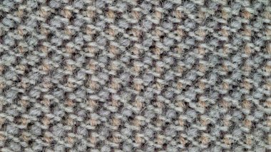 Arka plan olarak kullanılacak kumaş dokusunun makro fotoğrafı. Kumaş soluk turuncu, gri ve beyaz ipliklerin karışımından yapılmış. Sentetik ve yün karışımı. Soyut desen.