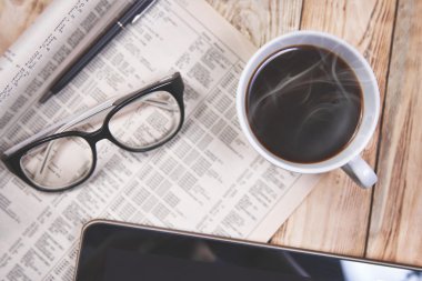 Tablet bilgisayar, kahve ve gazete masada