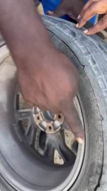 Yıpranmış araç lastiklerini dikkatle inceleyen, bozulmuş otomobil tekerleklerini yakından inceleyen teknisyen, güvenlik riskleri ve yedek ihtiyaçlar için kenarlarında aşınma olan yaşlanan lastikleri yakından inceliyor.