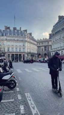 Louvre yakınlarındaki Paris sokak sahnesinde motosiklet sürücüsü ve park etmiş motosikletler, klasik Fransız mimarisi..