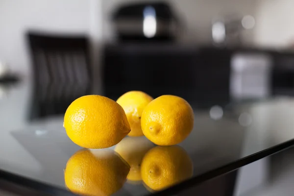 Three lemons on the glass table — Stock Photo, Image