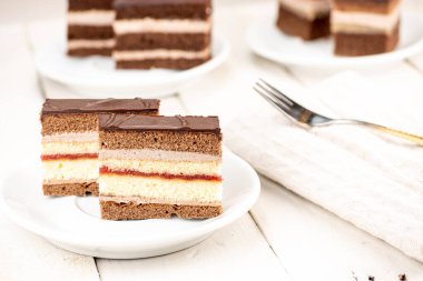 Çikolata soslu düğün pastası, kakao ve bisküvi hamuru, çikolata kreması ve çilek reçeli. Beyaz ahşap masada eski usul servis edilmiş. Lezzetli tatlı özellikle kahveyle..