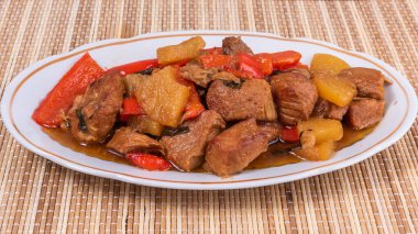 Bambu peçetedeki oval tabakta ananas ve dolma biberli domuz eti. Filipin mutfağı.