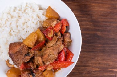 Adobo domuz eti, ananas ve biberli kaynamış pirinç ve ahşap arka planda, üst manzara, kopyalama alanı.