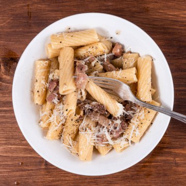 Pancetta 'lı makarna, siyah ahşap bir masada, yakın plan, üst manzara.