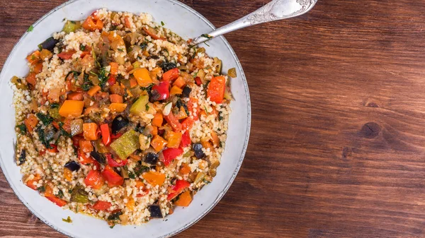Couscous with stews is a Moroccan and Tunisian dish. Couscous mixed with stewed vegetables in a large bowl close-up, top view, copy space