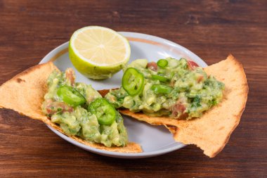 Ev yapımı guacamole. Avacado 'nun geleneksel Meksika aperatifi. Kızarmış tortilla parçaları üzerinde soğan ve domates.