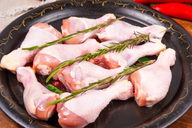 Çiğ tavuk budu, siyah kızartma tepsisinde, malzemeler ve baharatlar, üst manzara.