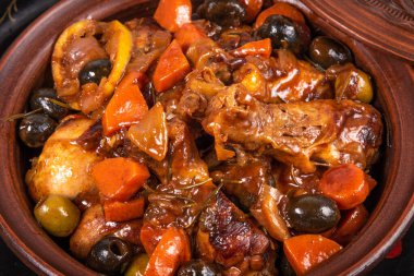 Tahta bir masa üzerinde baharatlı soslu zeytin ve sebzeli Cezayir güvecinde tavuk hazır olsun.