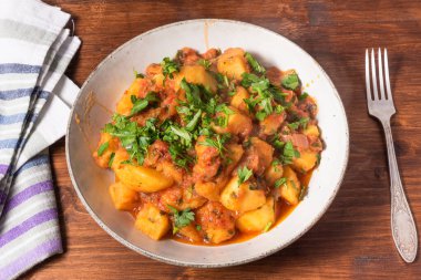 Yunan sebze ve patates güveci domates sosu içinde ahşap bir masada, üst tarafta, yakın plan.