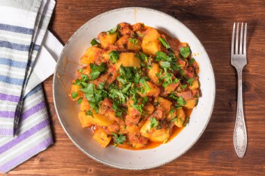 Yunan sebze ve patates güveci domates sosu içinde ahşap bir masada, üst tarafta, yakın plan.