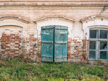 1915 'te inşa edilmiş eski bir tuğla evin alt katında pencere, kepenkler ve kırık bir pencere var.